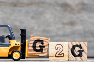Sarı Plastik forklift harf G (hükümet hükümete) tam Word G2g ahşap arka plan üzerinde tutun