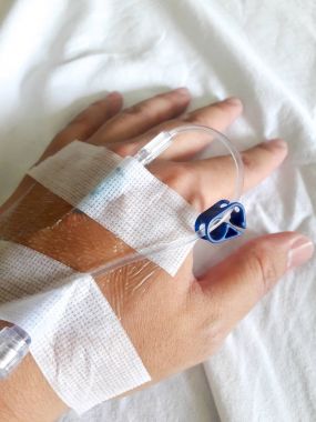 Beyaz kumaş arka plan üzerinde normal salin infüzyon tüp ile hasta el