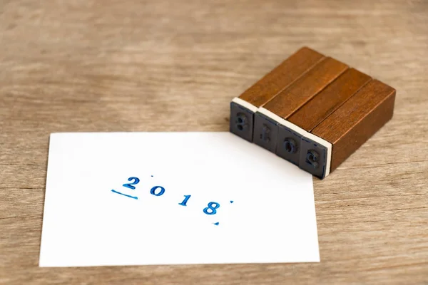 Blaue Aufschrift 2018 auf weißem Papier mit Holzblock-Stempel auf Holzgrund — Stockfoto