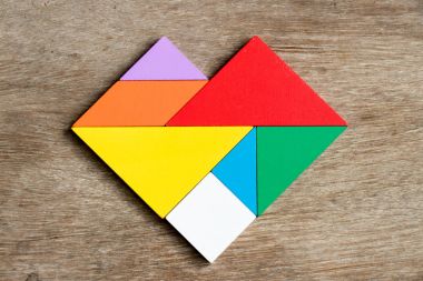 Ahşap arka plan üzerinde kalp şeklinde bulmaca renkli tangram