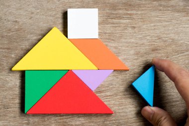 Renkli tangram bulmacanın ev şekli bekleyin için yerine getirmek ahşap arka plan (konsept yapı rüya evi, mutlu aile hayatı, gayrimenkul yatırım üzerinde)