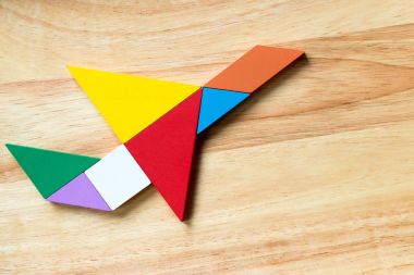 Uçak şekil ahşap arka plan üzerinde uçan renk tangram bulmacanın
