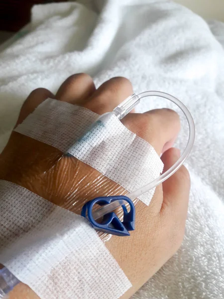 Pacienta ruku s trubicí normální fyziologický roztok na pozadí bílý ubrus — Stock fotografie