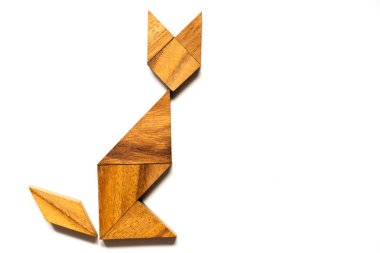 Ahşap tangram bulmacanın içinde şekil beyaz arka plan üzerinde oturan kedi