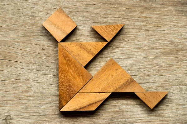 Wood tangram puzzle as man sit with read book or play mobile phone background