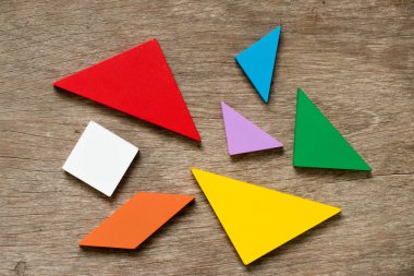 Ahşap arka plan şekli geliştirmek için renkli tangram bulmacanın bekle