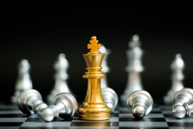 Satranç oyununda altın kral siyah zemin üzerinde başka bir gümüş takım ile karşı karşıya (Şirket stratejisi, iş zaferi veya karar kavramı)
