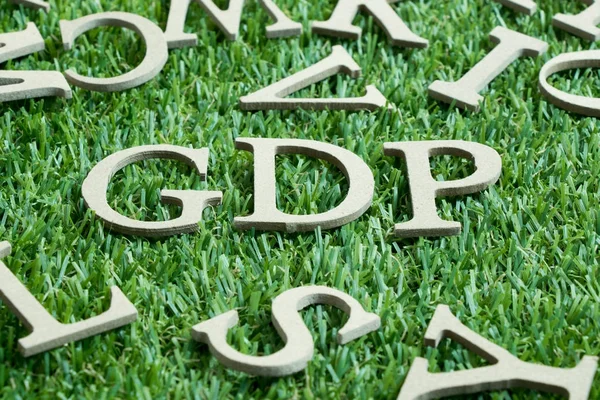 stock image Wood letter in word GDP (Abbreviation from Good distribution practice or Gross domestic product) on artificial green grass wit English alphabet background