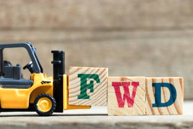 Oyuncak sarı forklift tutun kelime Fwd (ileri kısaltma) ahşap arka plan üzerinde tamamlamak için mektup blok F