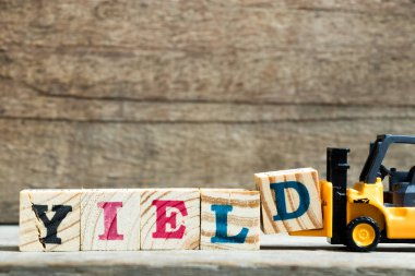 Sarı oyuncak forklift ahşap arka plan üzerinde tam word verim için mektup blok D tutun