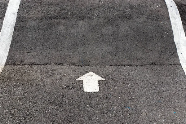 Pintura blanca en el símbolo de flecha de dirección hacia adelante sobre fondo de carretera de asfalto negro — Foto de Stock