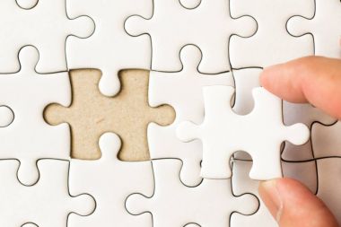 Arka plan beyaz düz jigsaw maç veya yerine getirmek için eksik parçası tutan el ile kapalı