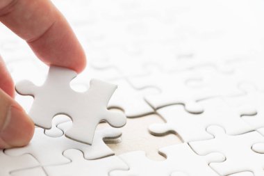 Arka plan beyaz düz jigsaw maç veya yerine getirmek için eksik parçası tutan el ile kapalı
