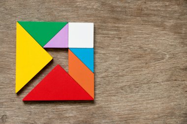Renkli tangram bulmacanın Meydanı ile ok yönünde şekli ahşap arka plan üzerinde içinde
