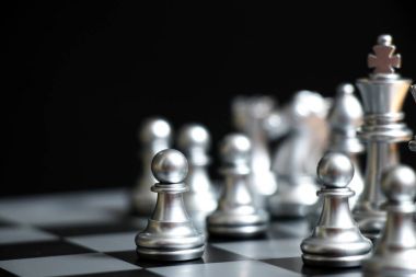 Gümüş piyon siyah arkaplan üzerine satranç oyununda ilk hamlededir (İş kararı kavramı, başlangıç veya başlangıç projesi)