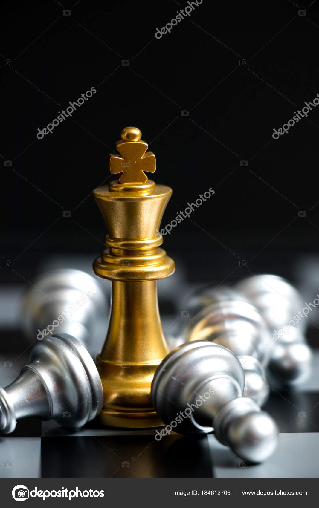 Gold king chess piece win over lying down pawn on black background