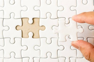 Arka plan beyaz düz jigsaw maç veya yerine getirmek için eksik parçası tutan el ile kapalı