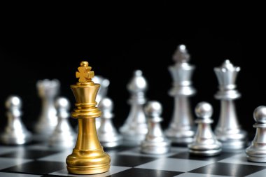 Satranç oyununda altın kral siyah zemin üzerinde başka bir gümüş takım ile karşı karşıya (Şirket stratejisi, iş zaferi veya karar kavramı)
