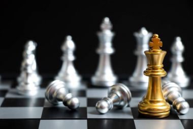 Satranç oyununda altın kral siyah zemin üzerinde başka bir gümüş takım ile karşı karşıya (Şirket stratejisi, iş zaferi veya karar kavramı)