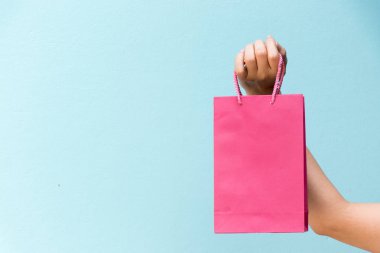İş kadını elini tut pembe alışveriş çantası mavi beton zemin üzerine