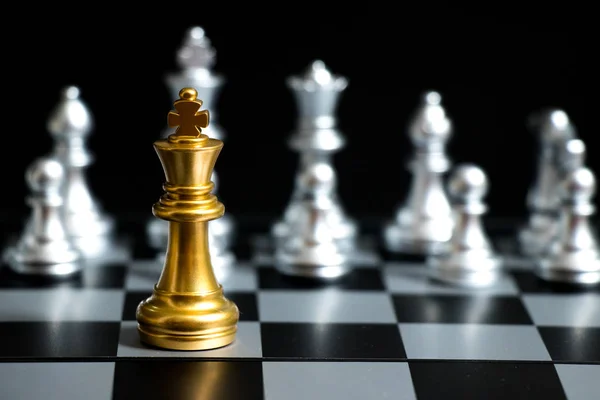 Gold King in chess game face with the another silver team on black background (Concept for company strategy, business victory or decision) — Stock Photo, Image