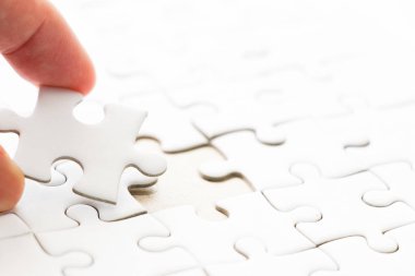 Arka plan beyaz düz jigsaw maç veya yerine getirmek için eksik parçası tutan el ile kapalı