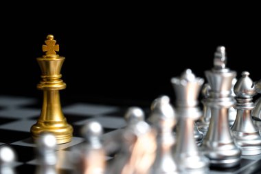 Satranç oyununda altın kral siyah zemin üzerinde başka bir gümüş takım ile karşı karşıya (Şirket stratejisi, iş zaferi veya karar kavramı)