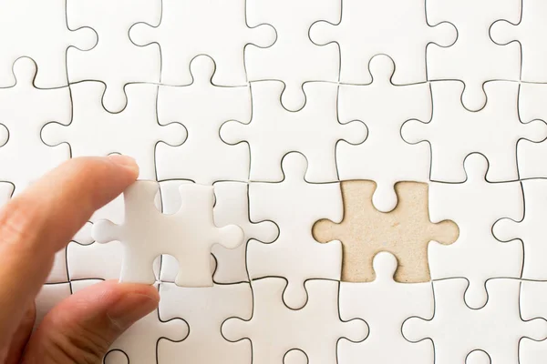 Geschlossen Hintergrund der weißen einfachen Puzzle mit der Hand, die fehlende Stück zu entsprechen oder zu erfüllen halten — Stockfoto
