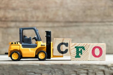 Oyuncak sarı forklift ahşap arka plan üzerinde kelime Cfo (kısaltma in Chief Financial Officer) tamamlamak için mektup blok C tutun