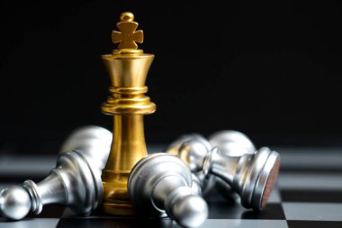Satranç oyununda altın kral siyah zemin üzerinde başka bir gümüş takım ile karşı karşıya (Şirket stratejisi, iş zaferi veya karar kavramı)