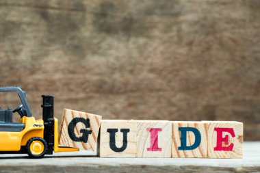 Sarı oyuncak forklift tutun word Kılavuzu ahşap arka plan üzerinde tamamlamak için mektup blok g