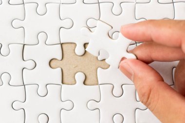 Arka plan beyaz düz jigsaw maç veya yerine getirmek için eksik parçası tutan el ile kapalı