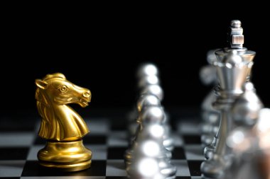 Siyah arka plan (konsept şirket stratejisi, iş zafer veya karar için başka bir gümüş takım ile satranç oyun yüzüne altın at)