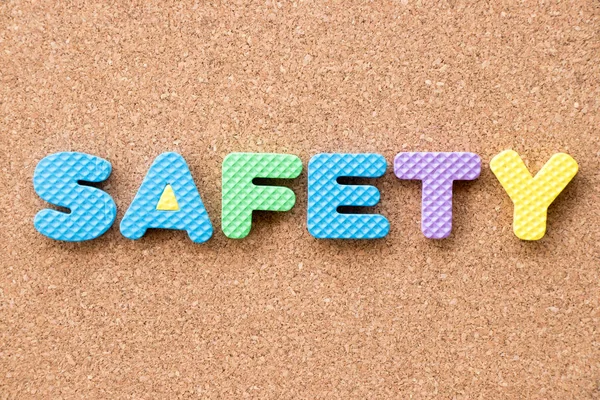 Alfabeto de espuma de brinquedo de cor em segurança de palavras no fundo da placa de cortiça — Fotografia de Stock