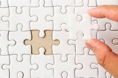 Arka plan beyaz düz jigsaw maç veya yerine getirmek için eksik parçası tutan el ile kapalı