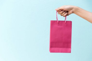 İş kadını elini tut pembe alışveriş çantası mavi beton zemin üzerine