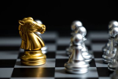 Siyah arka plan (konsept şirket stratejisi, iş zafer veya karar için başka bir gümüş takım ile satranç oyun yüzüne altın at)