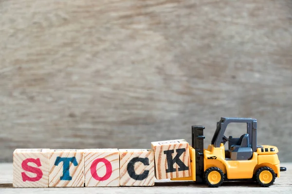 Spielzeug Gabelstapler halten Buchstabe Block k, um Wortbestand auf Holz Hintergrund zu vervollständigen — Stockfoto