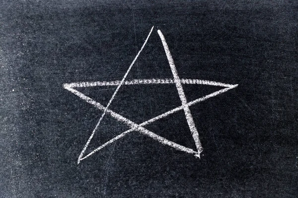 White chalk drawing in star shape on black board background