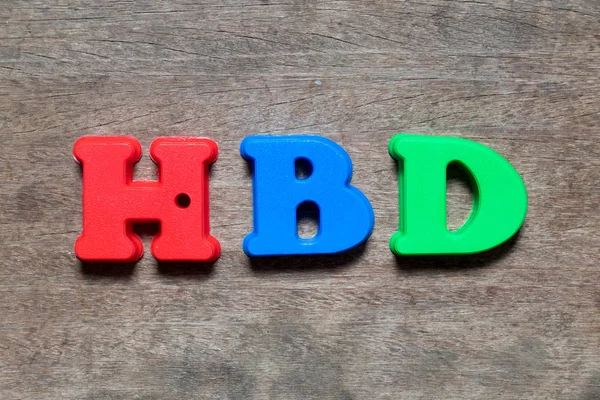 Color alphabet in word HBD (Abbreviation of happy birthday) on wood background
