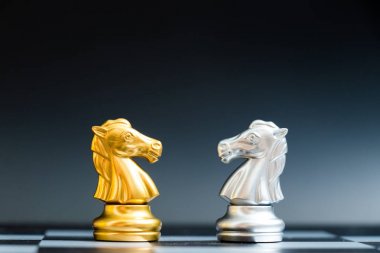 Satranç tahtası siyah zemin üzerine altın ve gümüş at satranç parça yüzüne