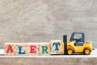 Oyuncak forklift tutun ahşap arka plan alarma kelime tamamlamak için mektup blok T