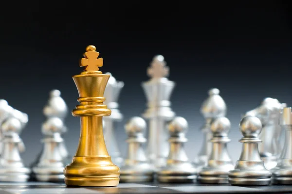 Rey de oro pieza de ajedrez cara a otro equipo de plata sobre fondo negro —  Fotos de Stock