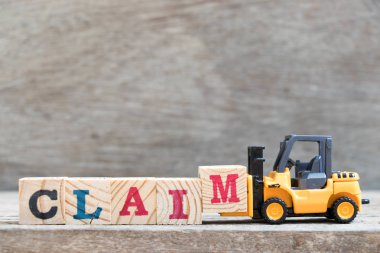 Oyuncak forklift harf bloğu M 'yi ahşap arkaplan üzerindeki kelime iddiasını tamamlamak için tut