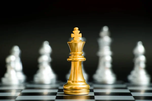 Gold king in chess game face with the another silver team on black background (Concept for company strategy, business victory or decision) — Stock Photo, Image