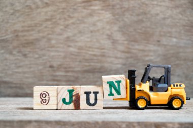 Ahşap arka plan (Konsept için takvim tarihi Haziran ayında 9 Haziran kelime tamamlamak için oyuncak forklift tutun blok N)