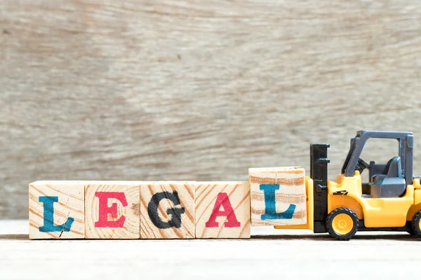 Spielzeug Gabelstapler halten Buchstabe Block l zu vervollständigen Wort legal auf Holz Hintergrund — Stockfoto