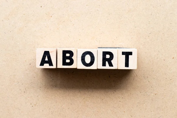 Blocco lettera in parola abortire su sfondo di legno — Foto Stock