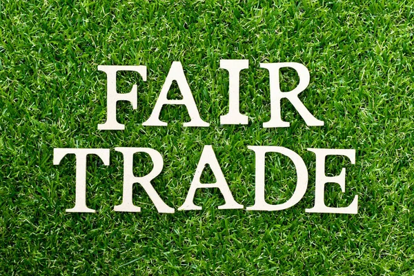 Dřevěné abeceda písmeno ve slově fair trade na zeleném travnatém pozadí — Stock fotografie