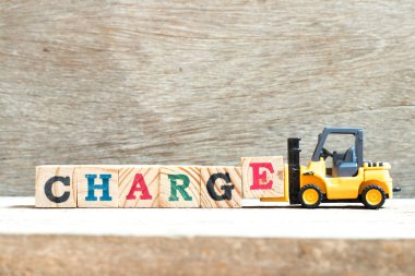 Oyuncak forklift ağaç arka planda kelime şarj tamamlamak için mektup bloğu e tutun